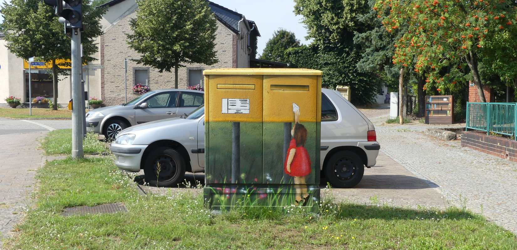 A girl with a letter in front of a postbox